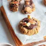 Cookies à la farine de châtaigne sans gluten garnis de pépites de chocolat fondant et d'éclats de noix sur du papier cuisson