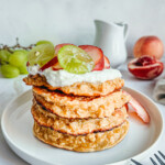 Pile de pancakes aux flocons d'avoine sans gluten décorés de crème, de raisins verts et de nectarines.