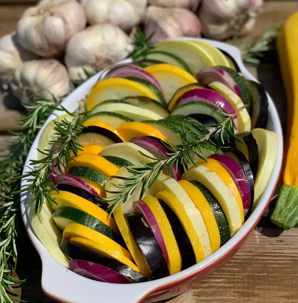Tian de légumes du soleil coloré et fondant avec aubergine courgette jaune et tomates anciennes dans un plat blanc