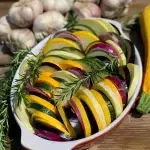 Tian de légumes du soleil coloré et fondant avec aubergine courgette jaune et tomates anciennes dans un plat blanc
