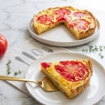 Quiche à la tomate sans gluten avec pâte brisée au lupin, rondelles de tomate et appareil crémeux au fromage, part coupée sur assiette blanche