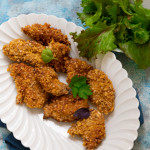 Poulet croustillant sans gluten pané aux pétales de maïs doré et croustillant avec salade verte sur assiette blanche