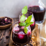 Bissap jus de fleurs d'hibiscus rouge intense avec glaçons et menthe fraîche dans des verres sur planche en bois