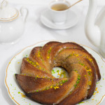 Gâteau amande sans gluten en forme de couronne avec un glaçage blanc brillant et des zestes de citron vert et d'orange