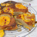 Gâteau moelleux à l'abricot sans gluten doré avec abricots caramélisés et fleurs comestibles sur grille de refroidissement