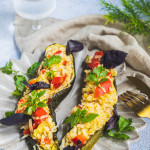 Courgettes farcies végétaliennes et sans gluten en bateaux avec farce de riz, poivron rouge et herbes fraîches sur assiette texturée