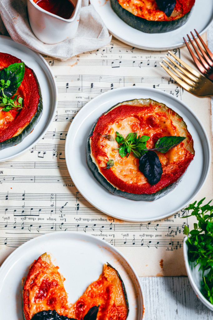 Pizza courgette sans gluten avec sauce tomate, mozzarella fondue et basilic frais, servie sur assiette blanche