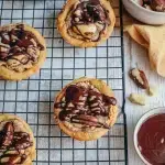Tartelettes aux noix du Brésil sans gluten croustillantes avec un nappage de chocolat noir fondu et des éclats de noix sur une grille