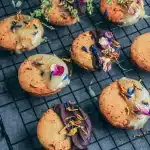 Biscuits à la rose sans gluten et vegan à moitié nappés de chocolat noir et blanc, décorés de pétales de fleurs séchées sur une grille
