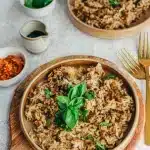 Riz sauté à l'aubergine sans gluten vegan garni de feuilles de basilic frais dans un bol en terre cuite