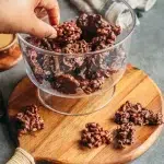 Bouchées croustillantes chocolat cacahuète sans gluten dans un bol en verre avec pétales de maïs enrobés de chocolat noir