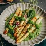 Asperges blanches rôties sans gluten sur sauce verte au yaourt grec avec basilic frais dans une assiette blanche