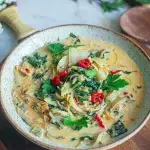 Curry de blettes au lait de coco sans gluten crémeux avec piment rouge et coriandre fraîche dans un bol en céramique verte