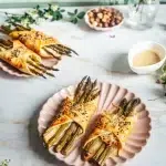 Feuilletés aux asperges vertes sans gluten dorés et croustillants avec chèvre fondant sur assiette rose