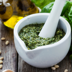 Pesto de fanes de carotte sans gluten vert dans un bocal, fanes fraîches à côté