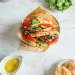 Bokits sans gluten garnis de légumes frais tomates salade et sauce sur papier kraft