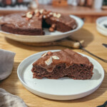 Gâteau au chocolat sans gluten fondant au mascarpone et chocolat noir 70% avec ganache et amandes effilées sur assiette blanche